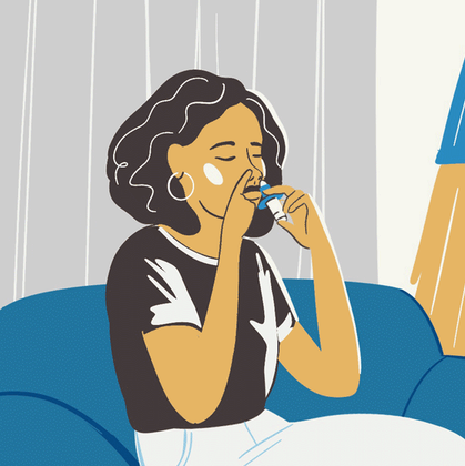 A woman is sitting on a blue couch using an inhaler.