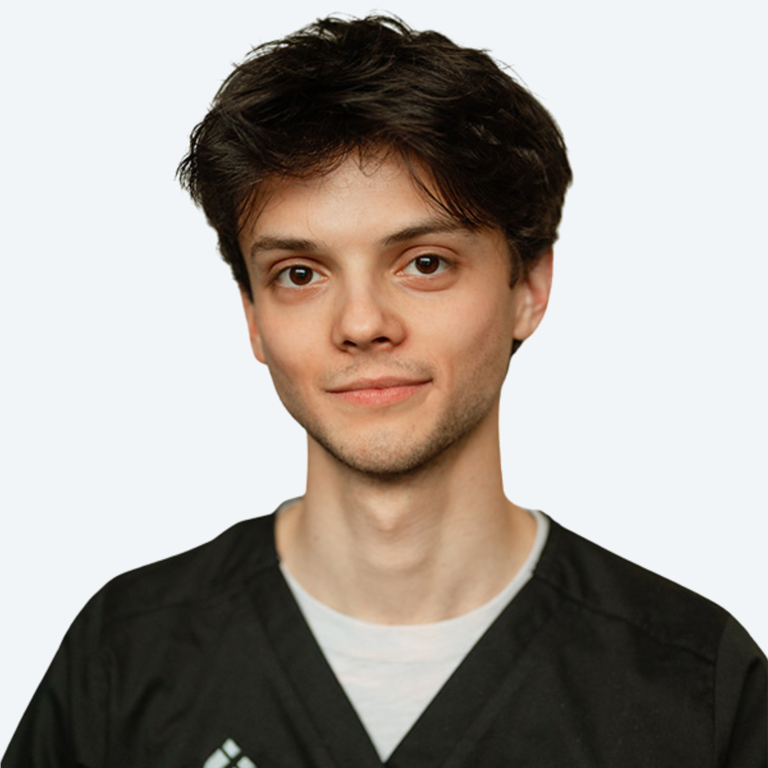 A young man wearing a black scrub top is smiling for the camera.