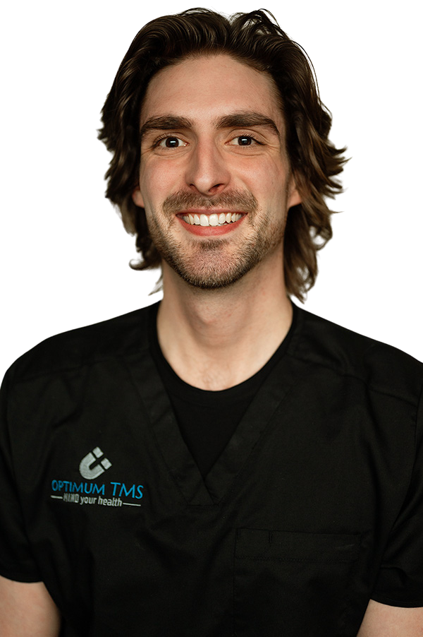 A man with long hair and a beard is wearing a black scrub top and smiling.