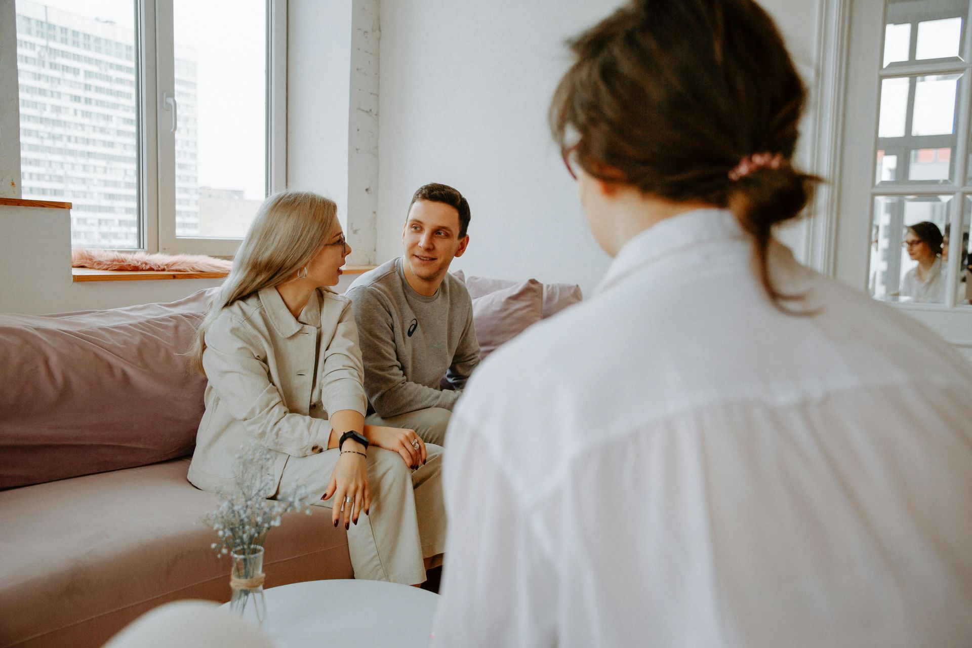 Therapist speaking with a seated couple in a bright living room during counseling session