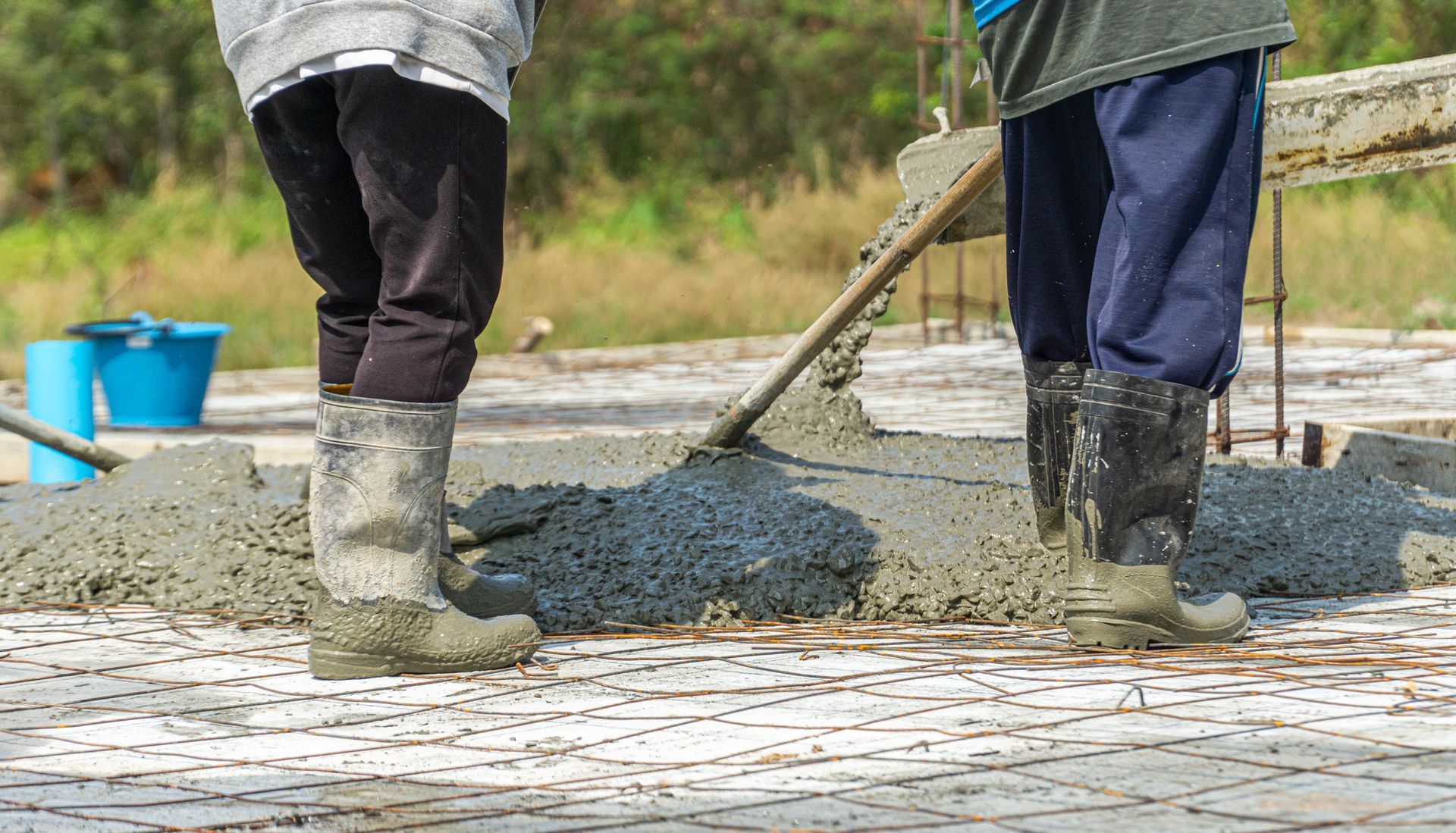 Two workers pouring concrete on a construction site.