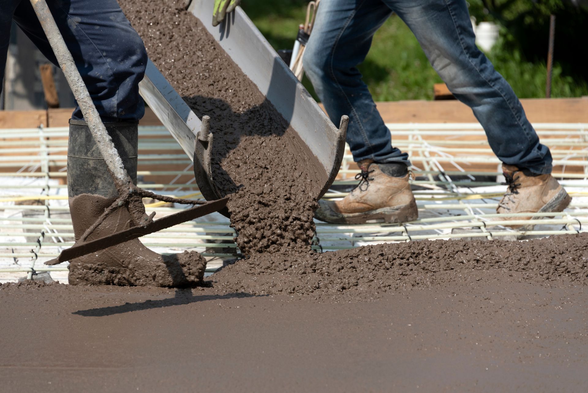 Workers pouring concrete on a construction site; concrete being poured over rebar.