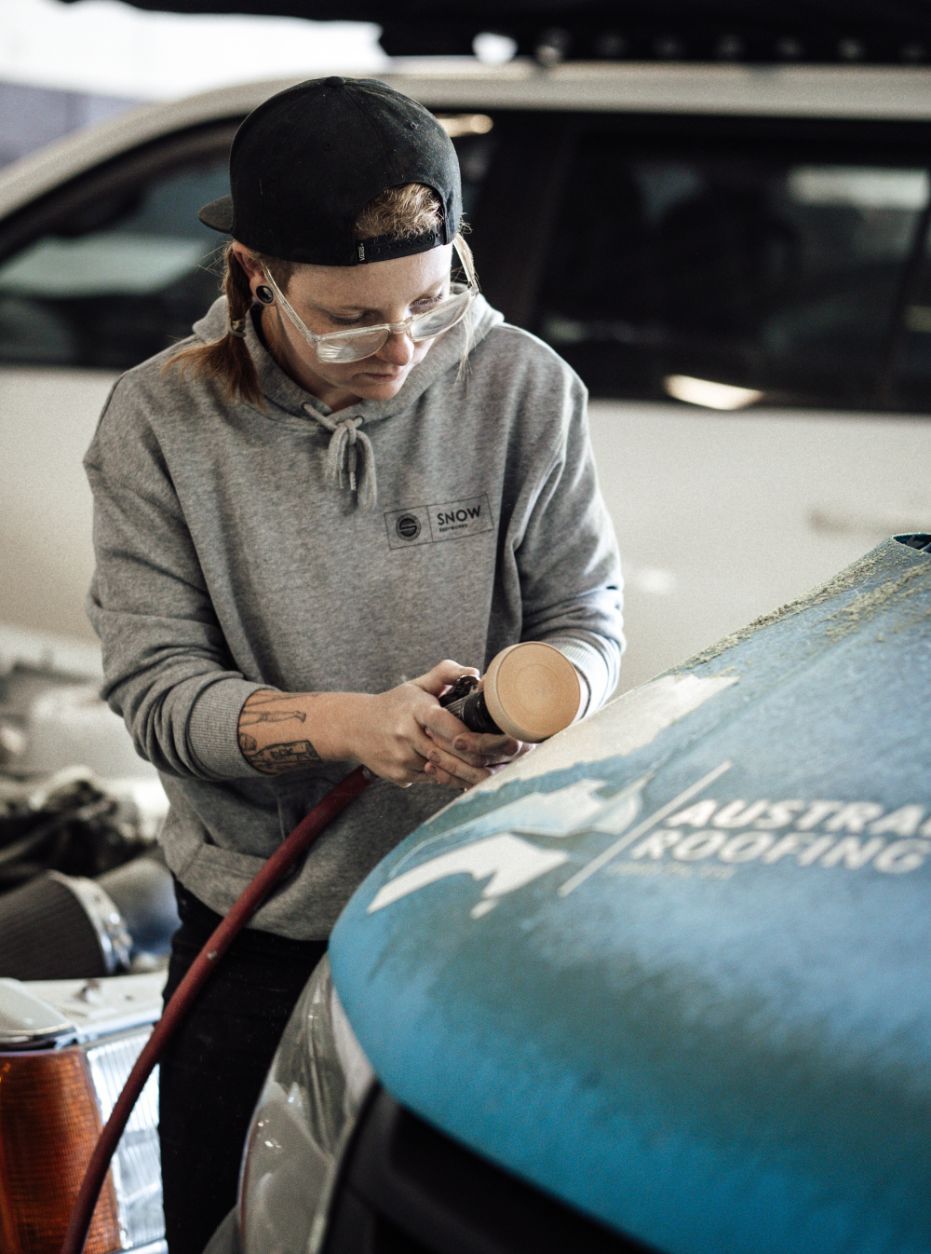 Woman Grinding Bonnet of Car — Panel Beaters in Southport, QLD
