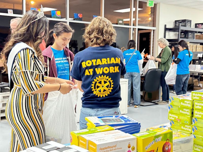 Volunteers in a warehouse package boxes, including a person in a navy blue 