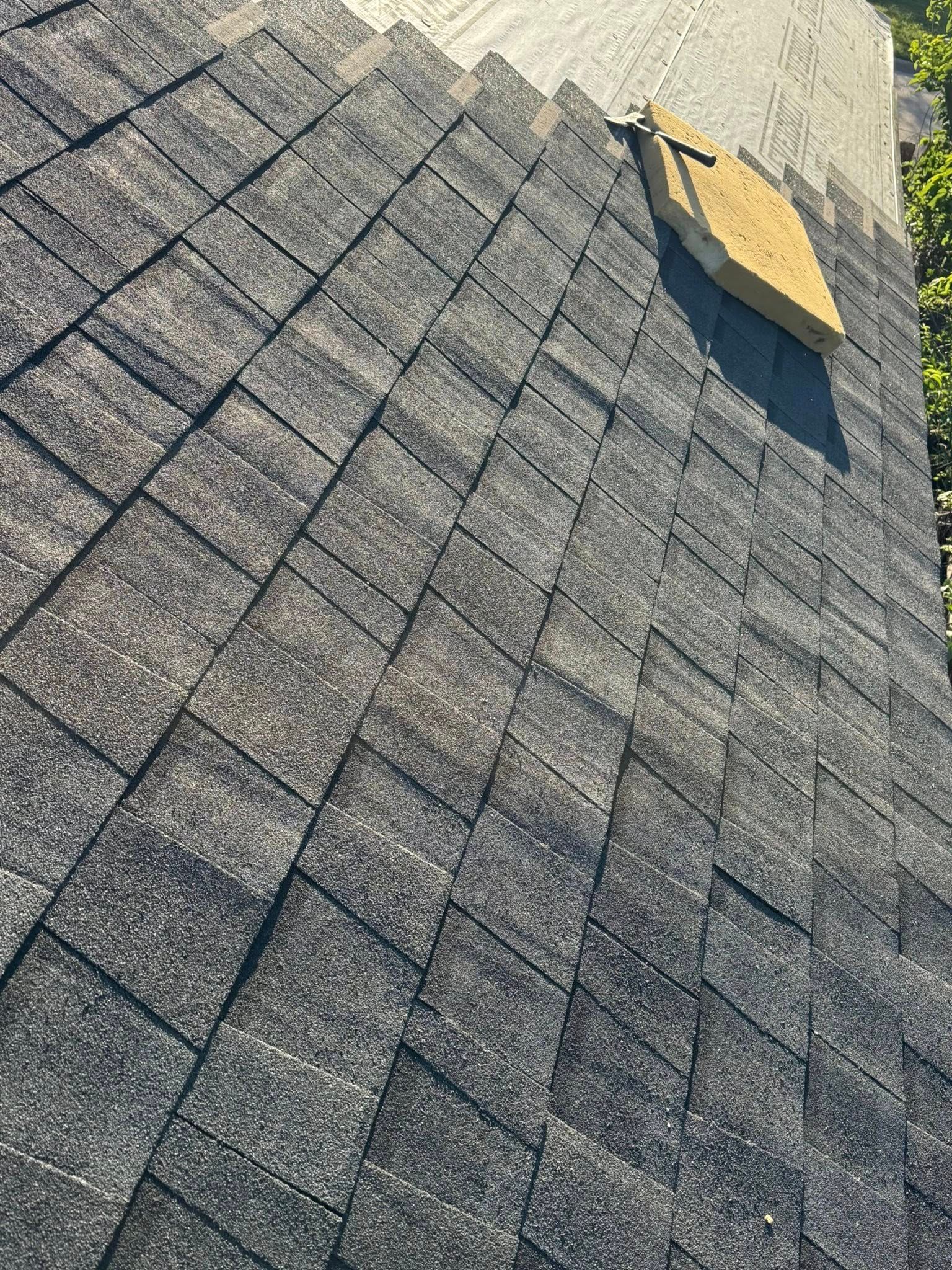 Gray shingled roof with a yellow vent near the top right, viewed at an angle