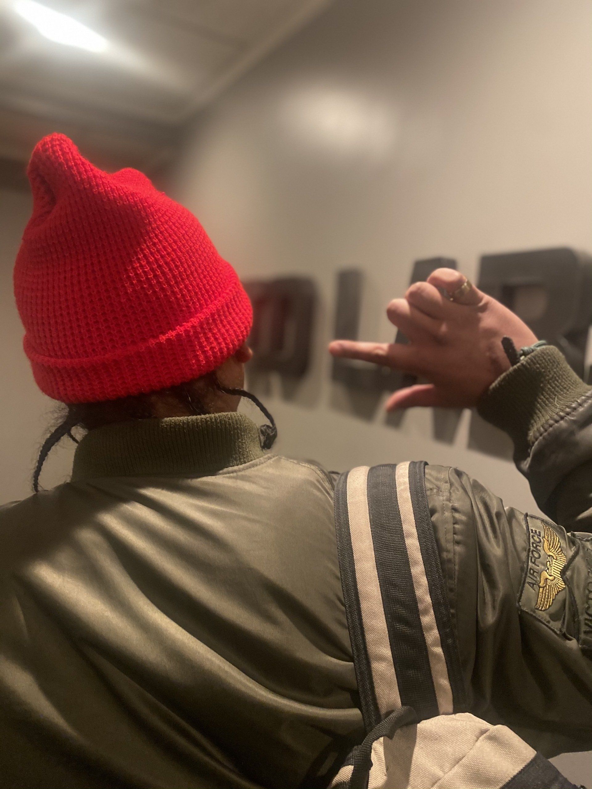 A person wearing a red beanie and a green jacket