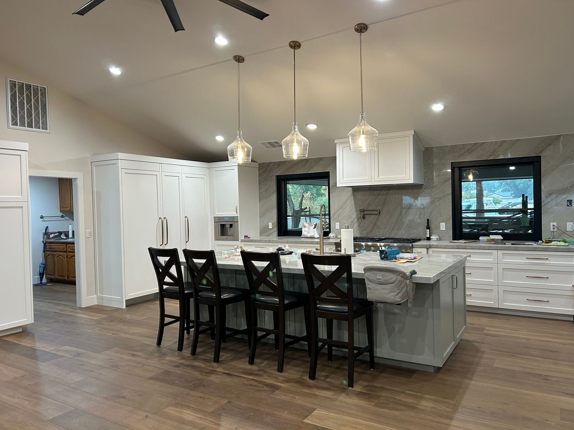 Room being painted, white walls, wooden floor. Ladder, paint supplies, and drop cloth are visible.