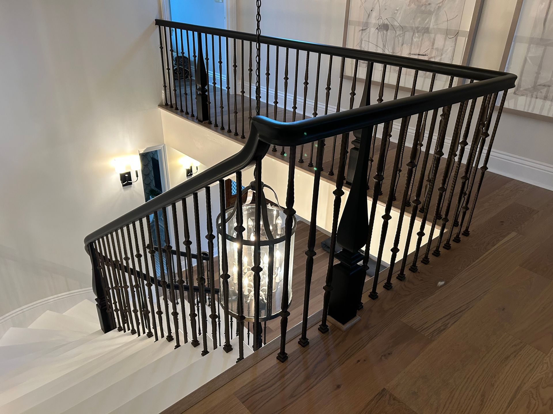 Staircase with black wrought iron railing, white steps, and a hanging light fixture.