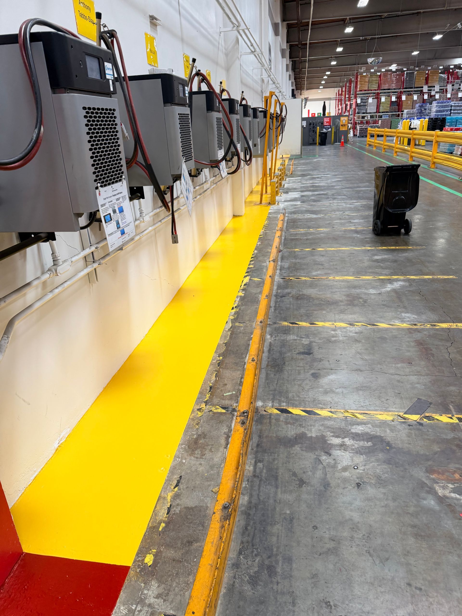 Yellow-painted industrial area with machinery and a marked walkway. Black box on floor.