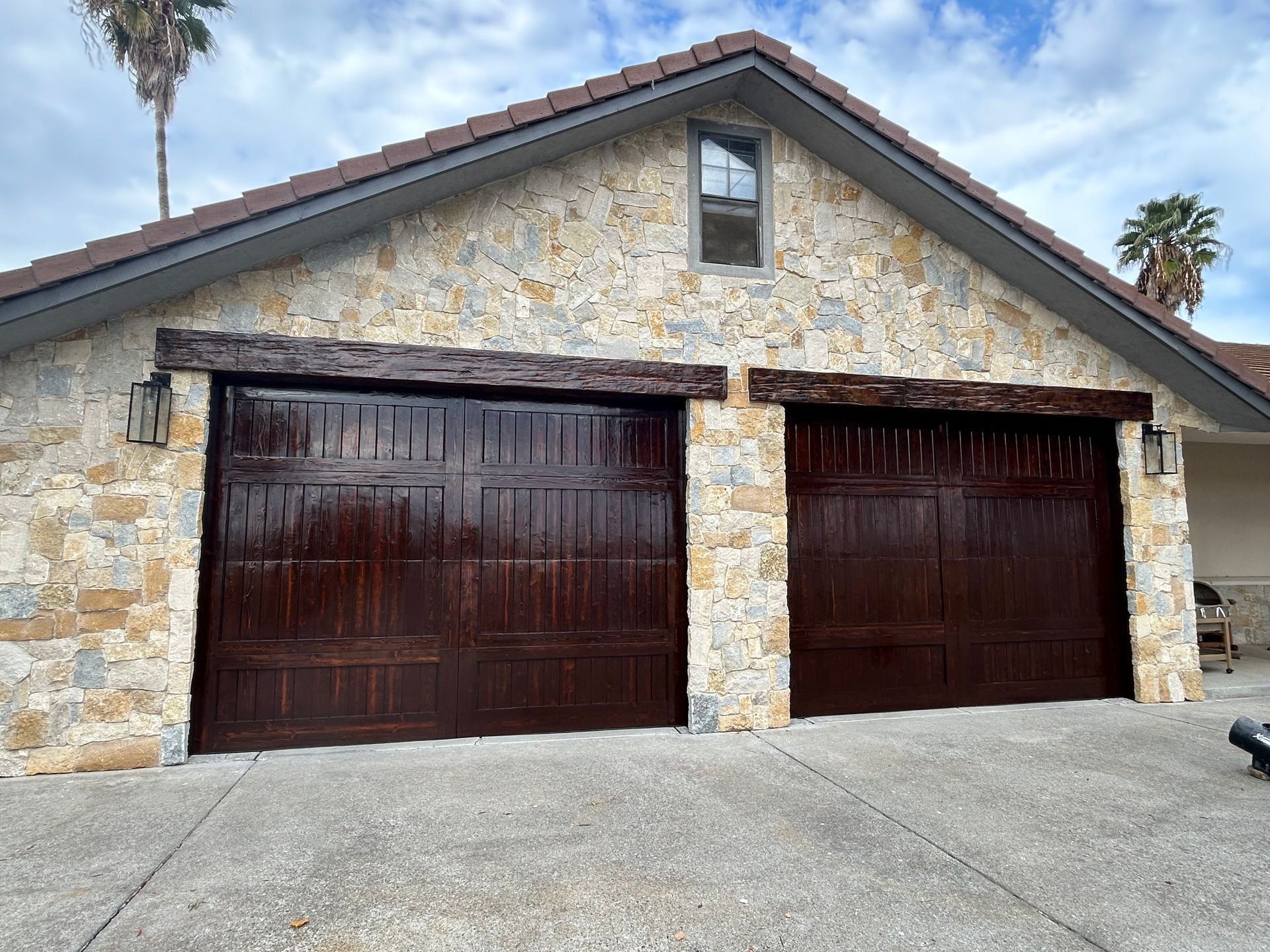 A person's hand using a paintbrush to paint white trim around a window frame.
