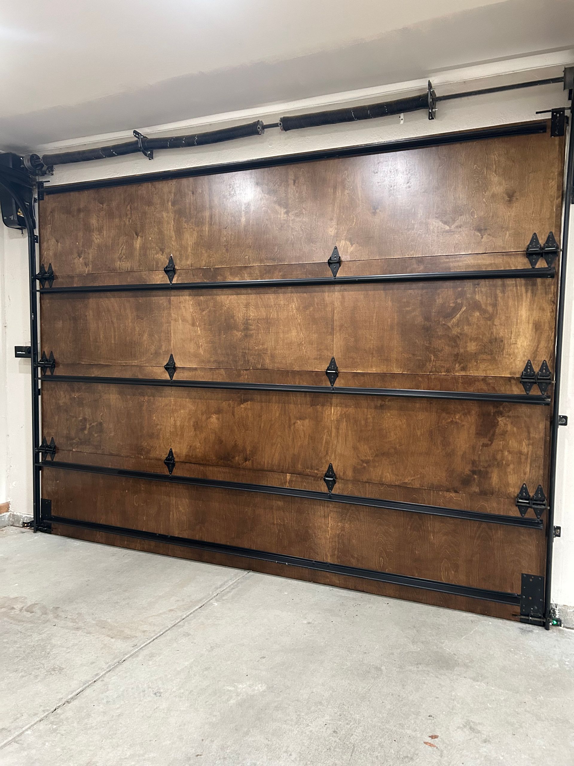 Wooden garage door with black metal trim and decorative accents.