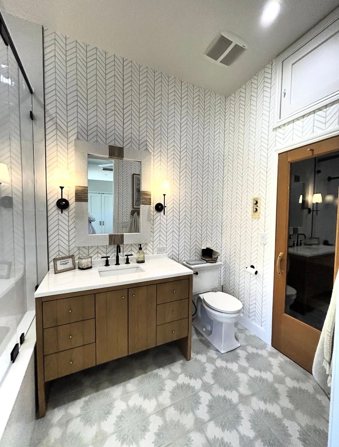 Two painters in white suits painting a room; one on a ladder taping a door frame, the other using a roller.