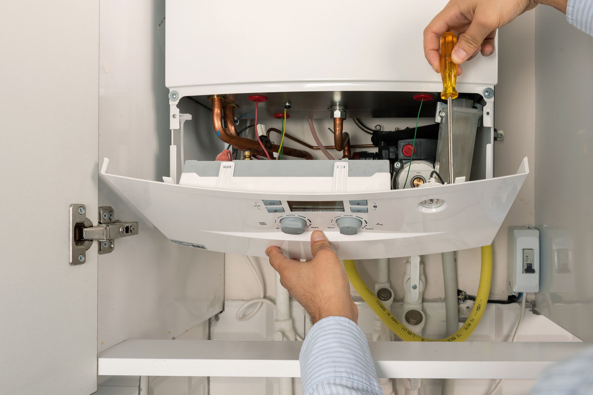 Heating contractor repairing wall-mounted combi gas boiler, adjusting components during maintenance. Heating contractor repairing wall-mounted combi gas boiler, adjusting components during maintenance.