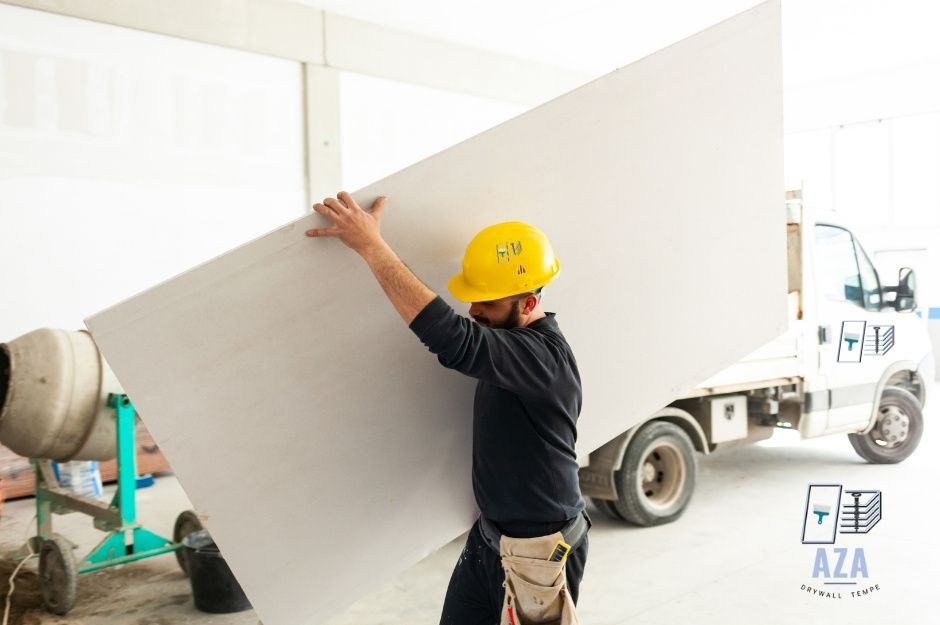 Male drywall worker lifting plasterboard for delivery project in residental home.