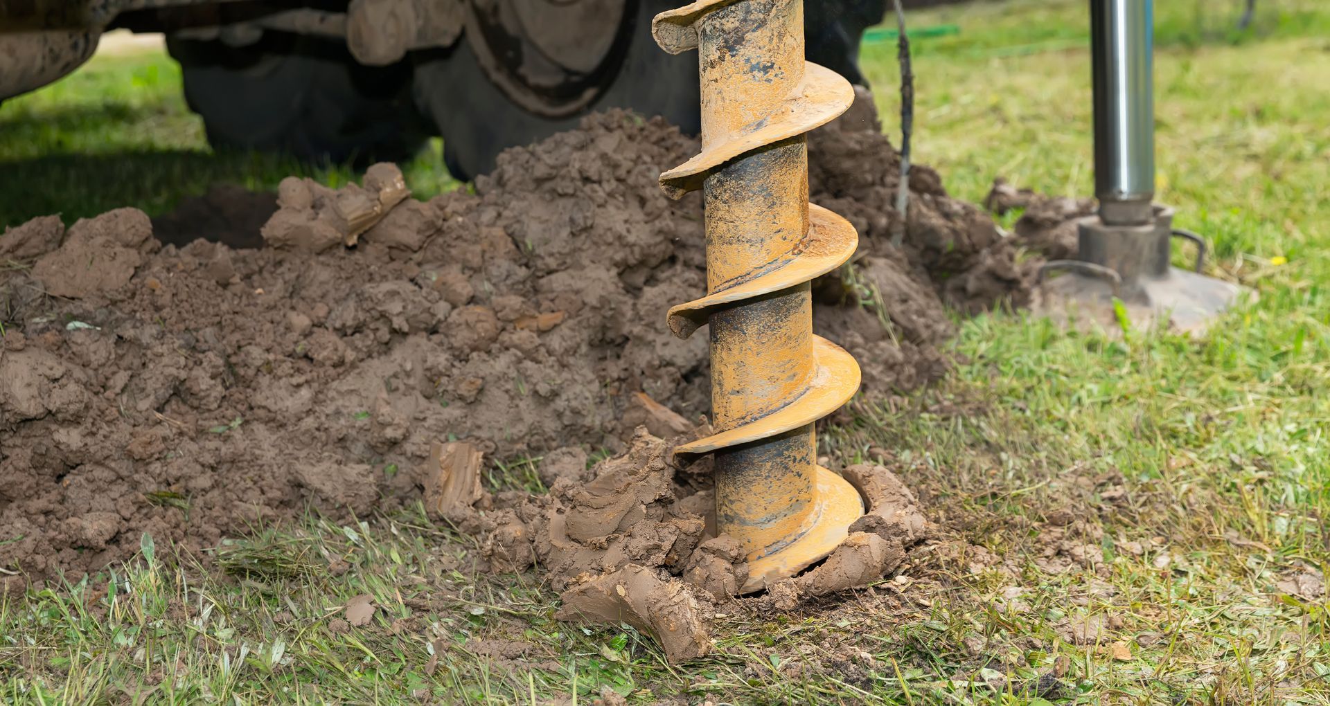 A heavy-duty auger lifts soil as it drills into the earth for a well installation.