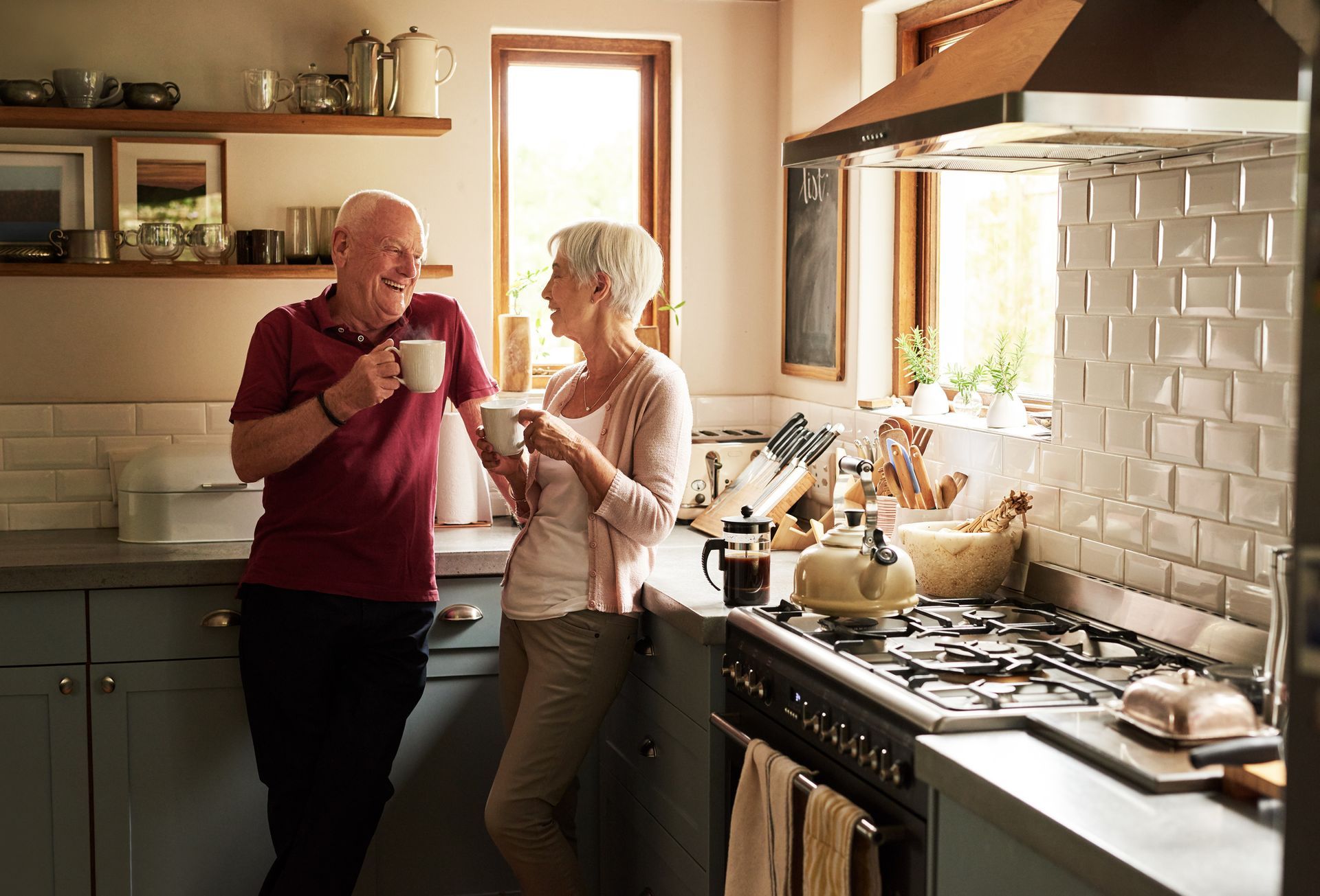 An elderly couple is standing in a kitchen drinking coffee. — Seattle, WA — Quality Plumbing