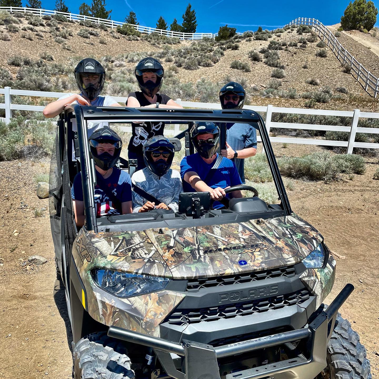 3 friends look off into the distant mountains with 2 UTV Polaris RZRs