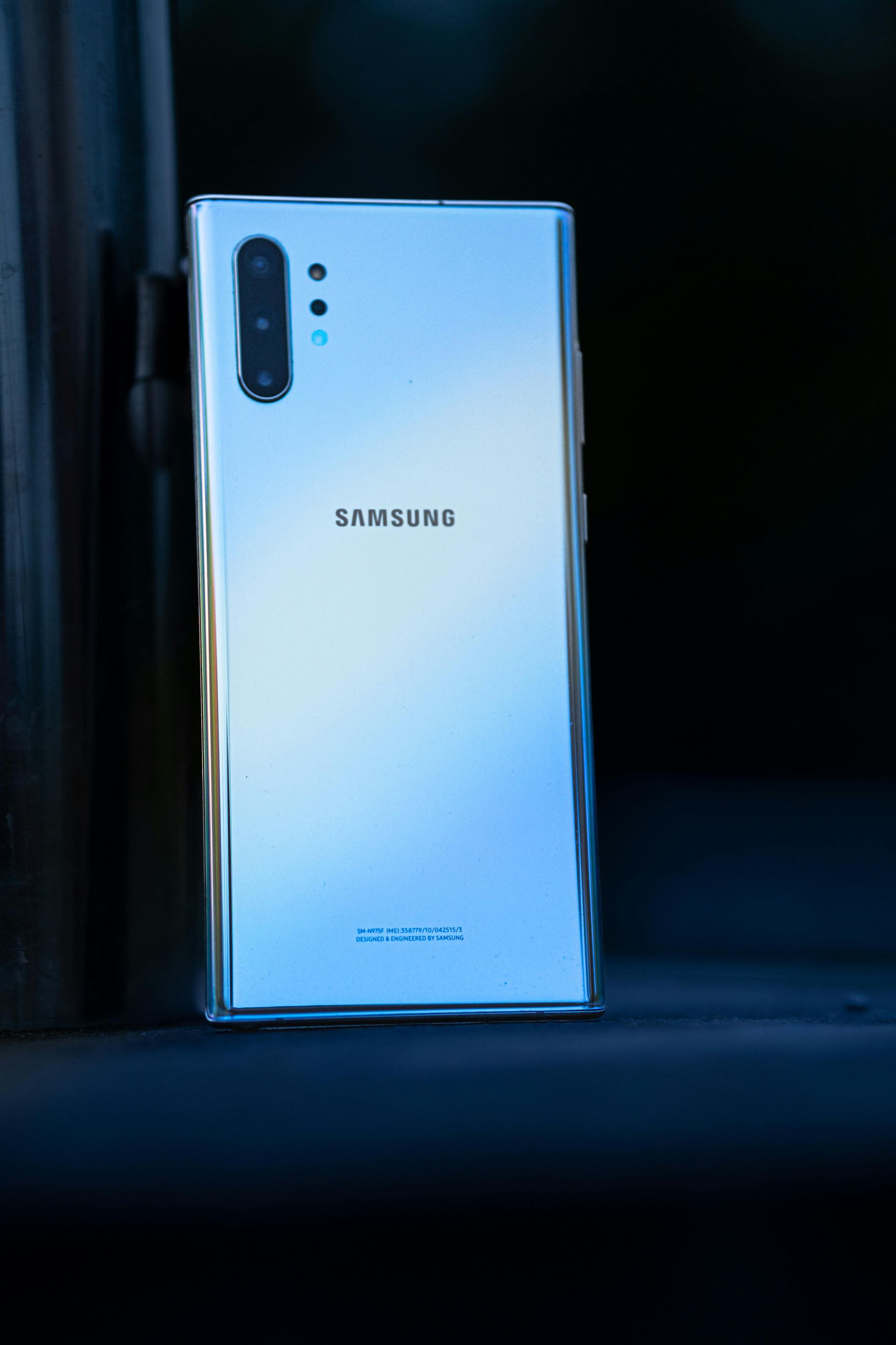El teléfono plateado de Samsung se apoya sobre una superficie oscura, mostrando su parte trasera, con múltiples cámaras.