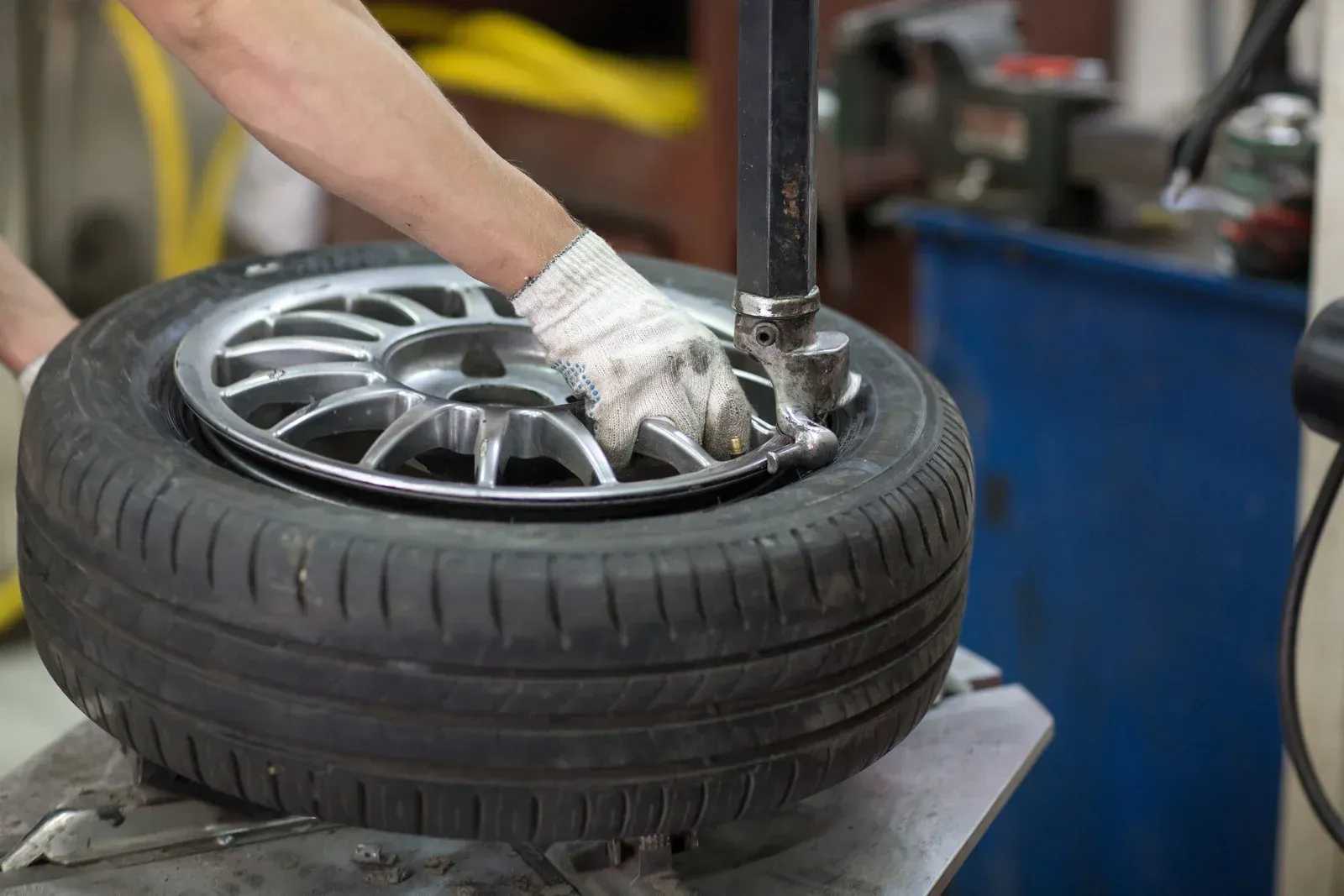 Person using a machine to remove a tire from a wheel rim.