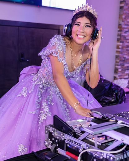 A woman in a purple dress is wearing headphones and a tiara.