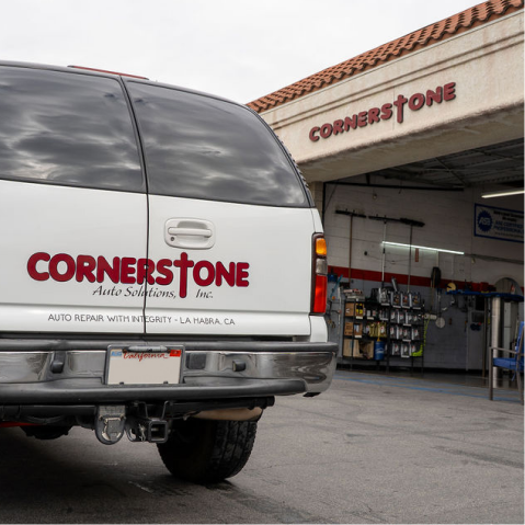 White vehicle parked in front of an auto repair shop with