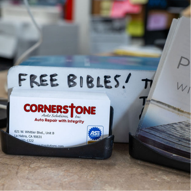 Business cards for Cornerstone Auto Solutions sit in a black holder next to a sign reading 