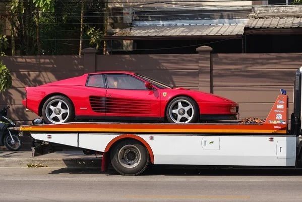 A red sports car is being towed by a tow truck.