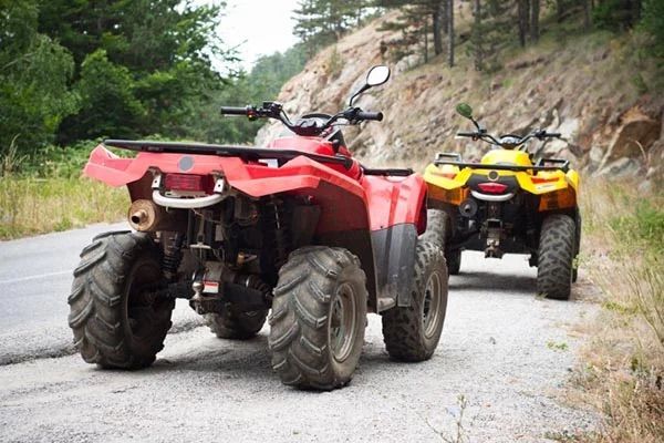 Two atvs are parked on the side of a road.