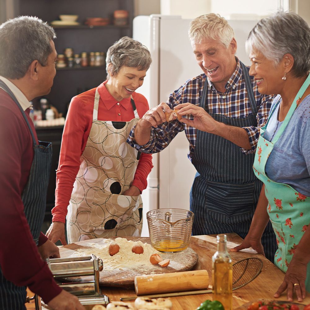 A group of senior citizens cooking together in a kitchen.