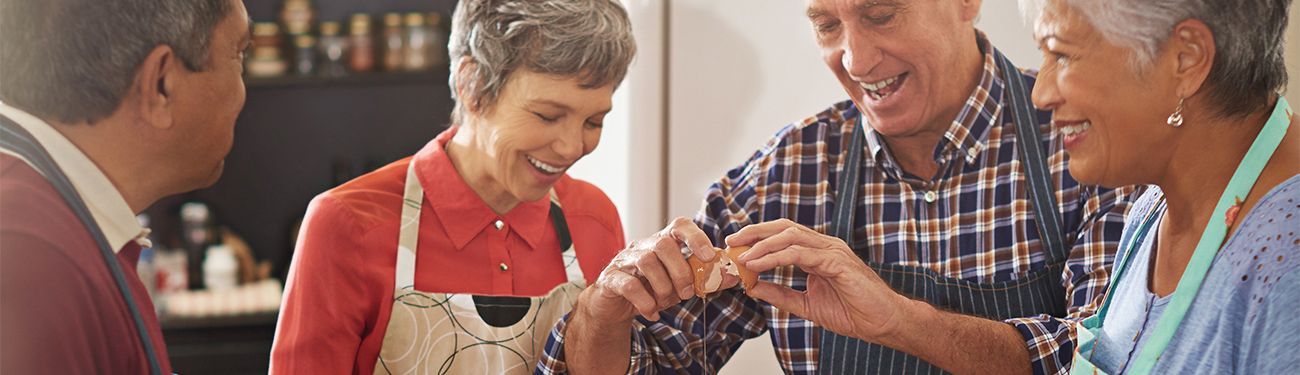 A group of senior citizens cooking together in a kitchen.
