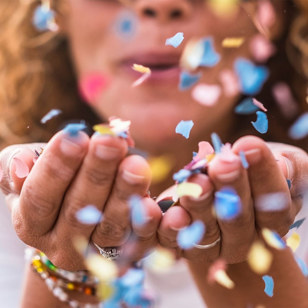 Woman blowing confetti from her hands