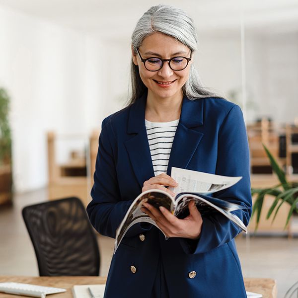 woman with grey hair reading a newsletter