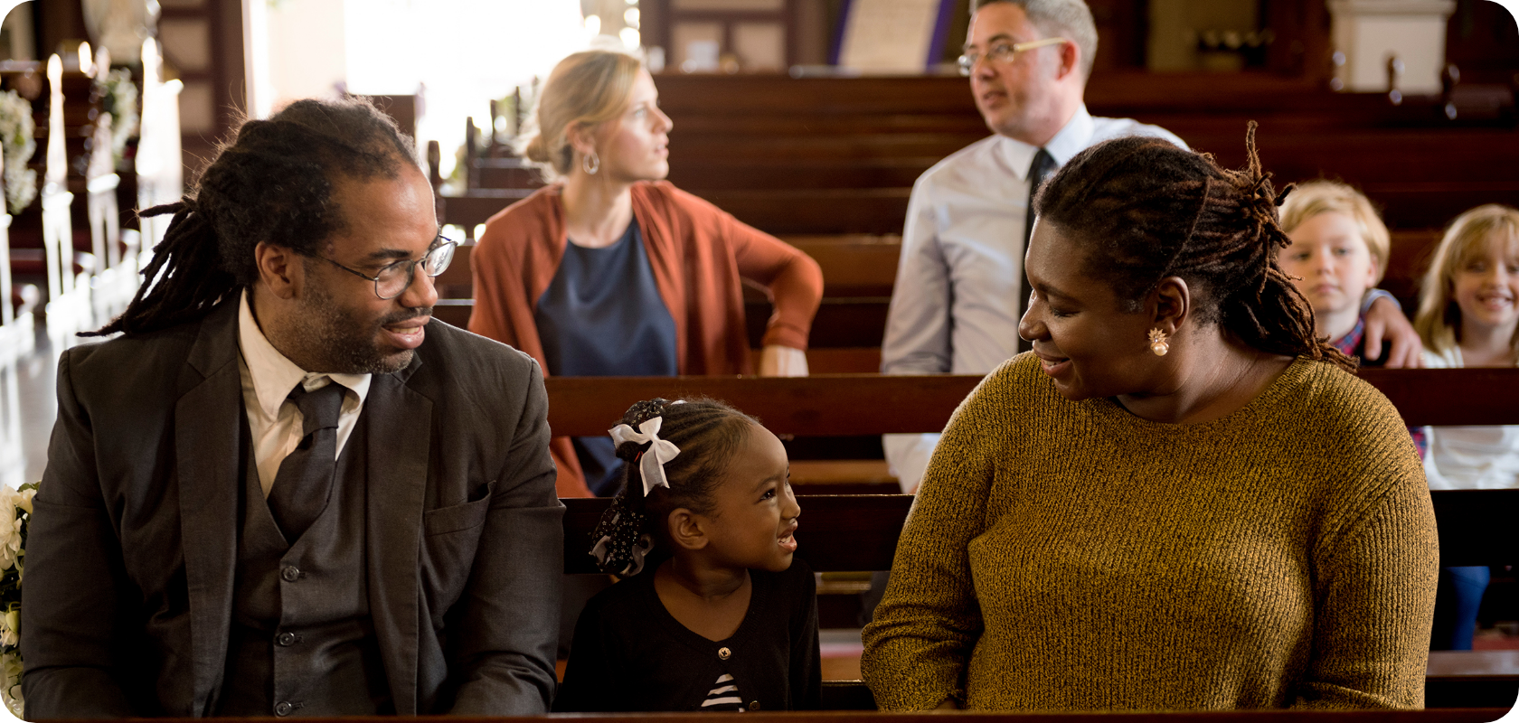 A group of families are sitting in a church talking to each other.