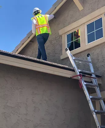 A man is standing on a newly installed roof by Four Peaks Roofing in Cape Coral