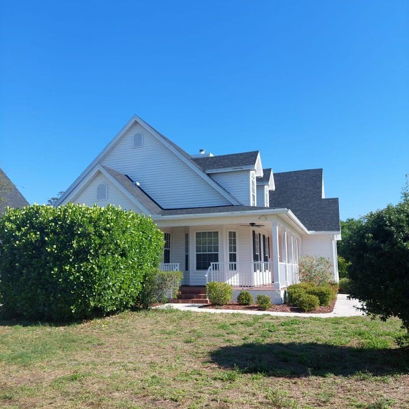 A white house with a black roof installed by Four Peaks Roofing in Fort Myers