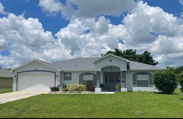 A white house with a gray roof installed by Four Peaks Roofing in Cape Coral