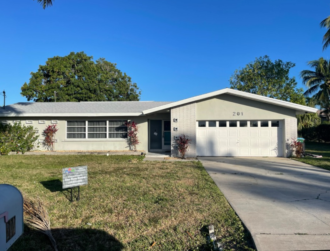 A white house with a new grey roof built by Four Peaks Roofing in Cape Coral