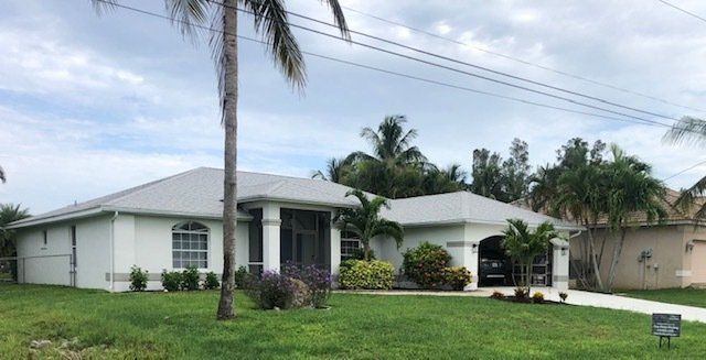 A white house with a new roof by Four Peaks Roofing in Fort Myers