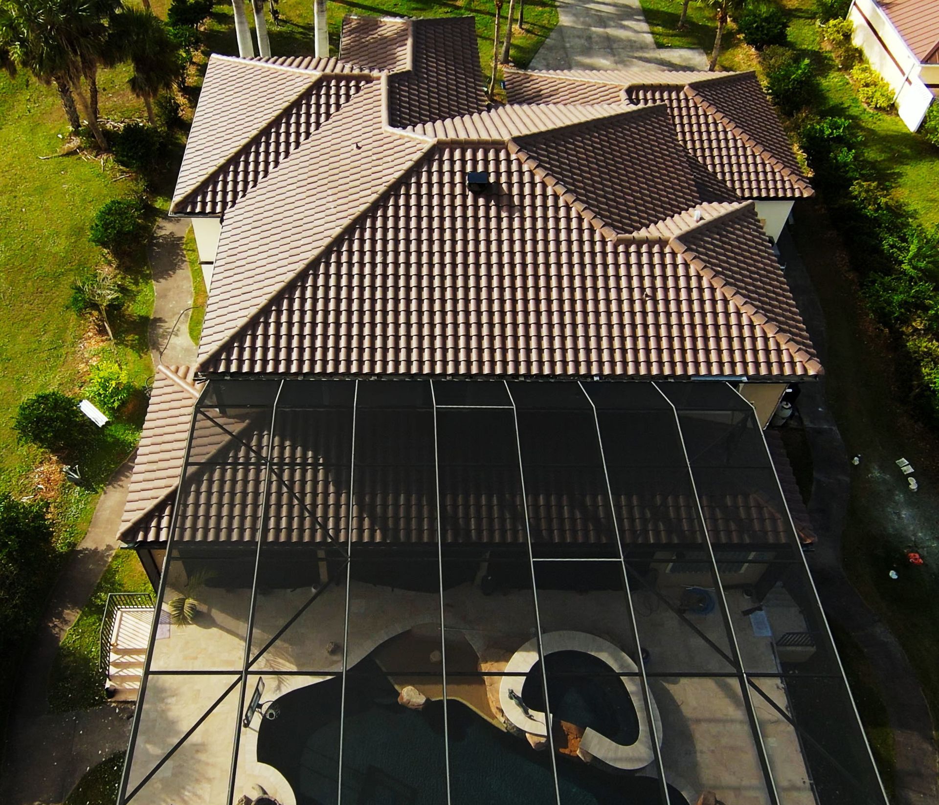An aerial view of a house with a screened in pool and new roof by Four Peaks Roofing in Cape Coral