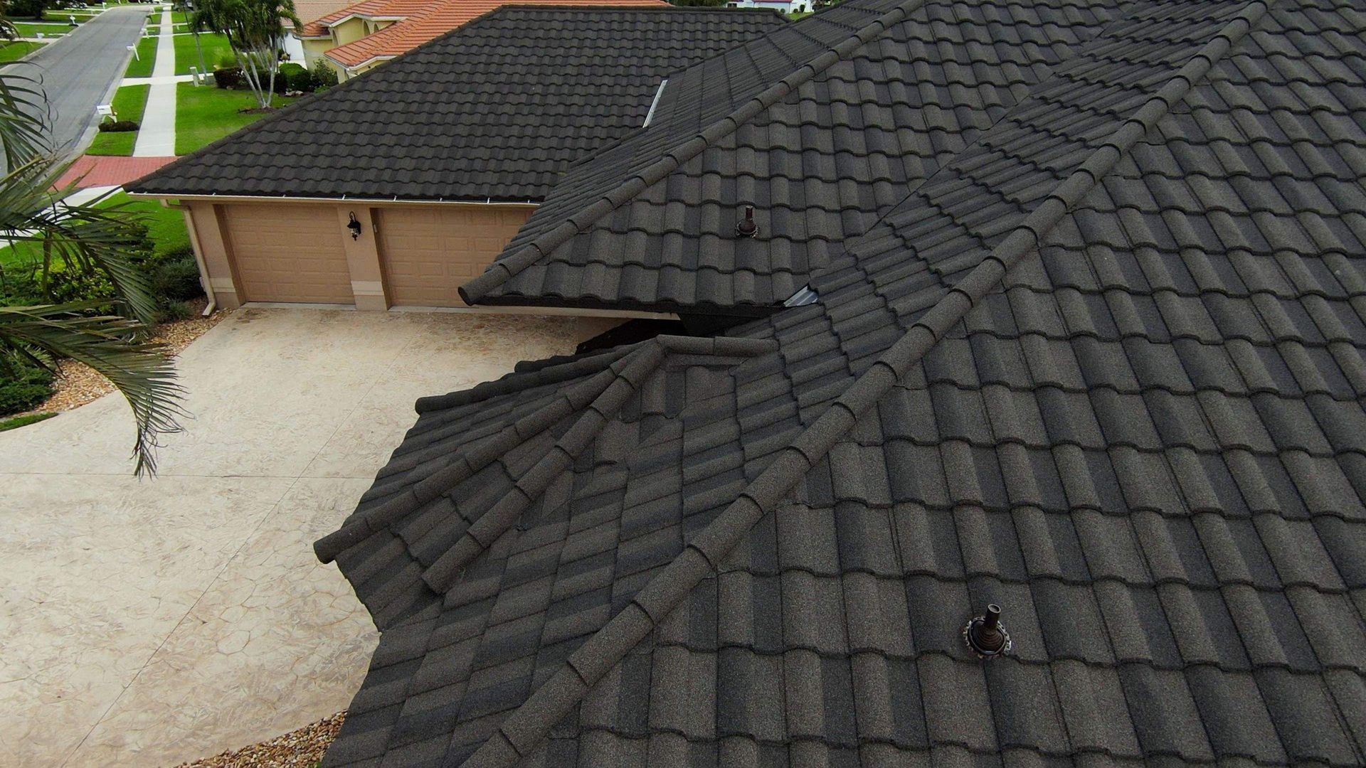 Dark gray tile roof on a house, driveway and garage visible.