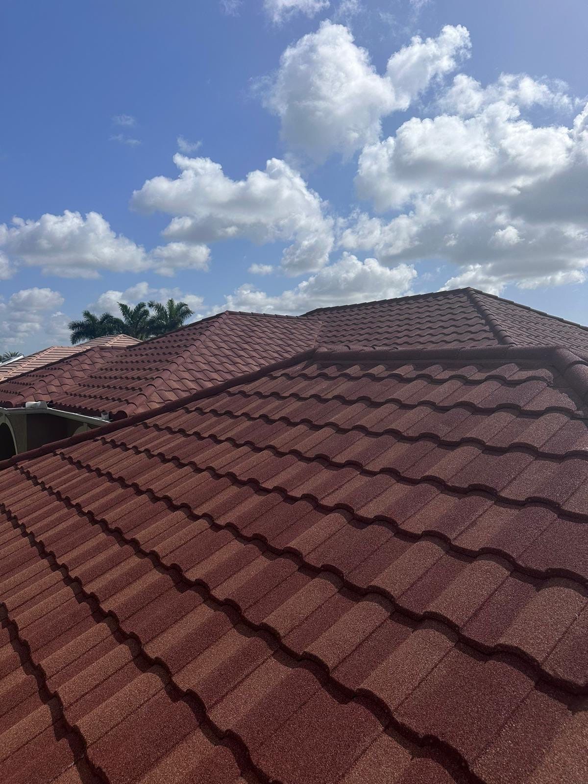 Red tile roof against a blue sky with scattered clouds.