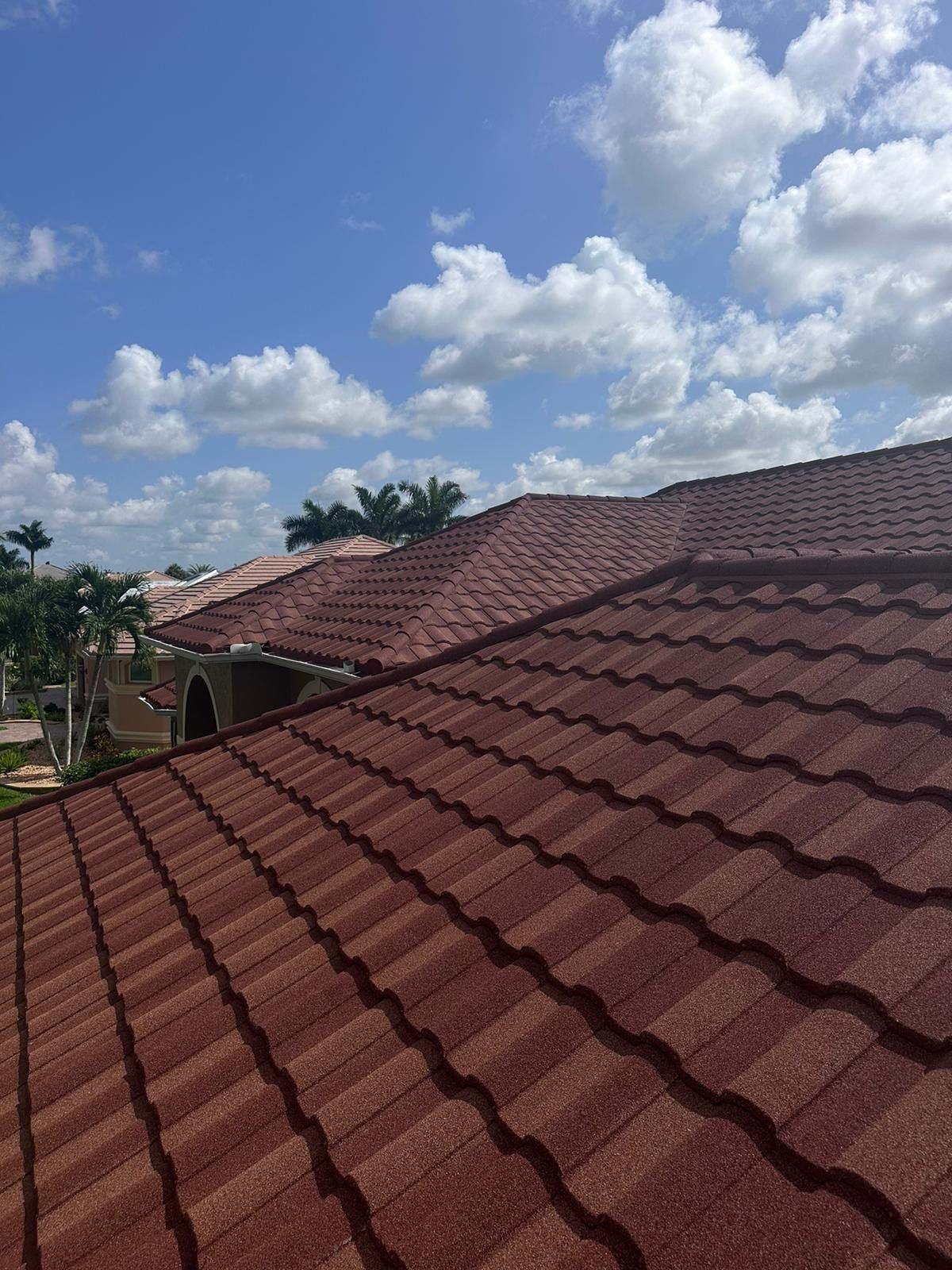Red tile roof under a partly cloudy blue sky.