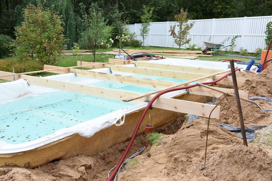 A swimming pool is being built in the dirt in a backyard.