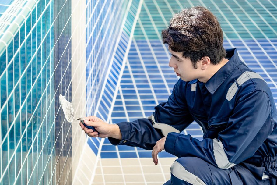 A man in a blue jumpsuit is working on a swimming pool.