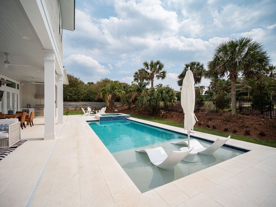 There is a large swimming pool in the backyard of a house.