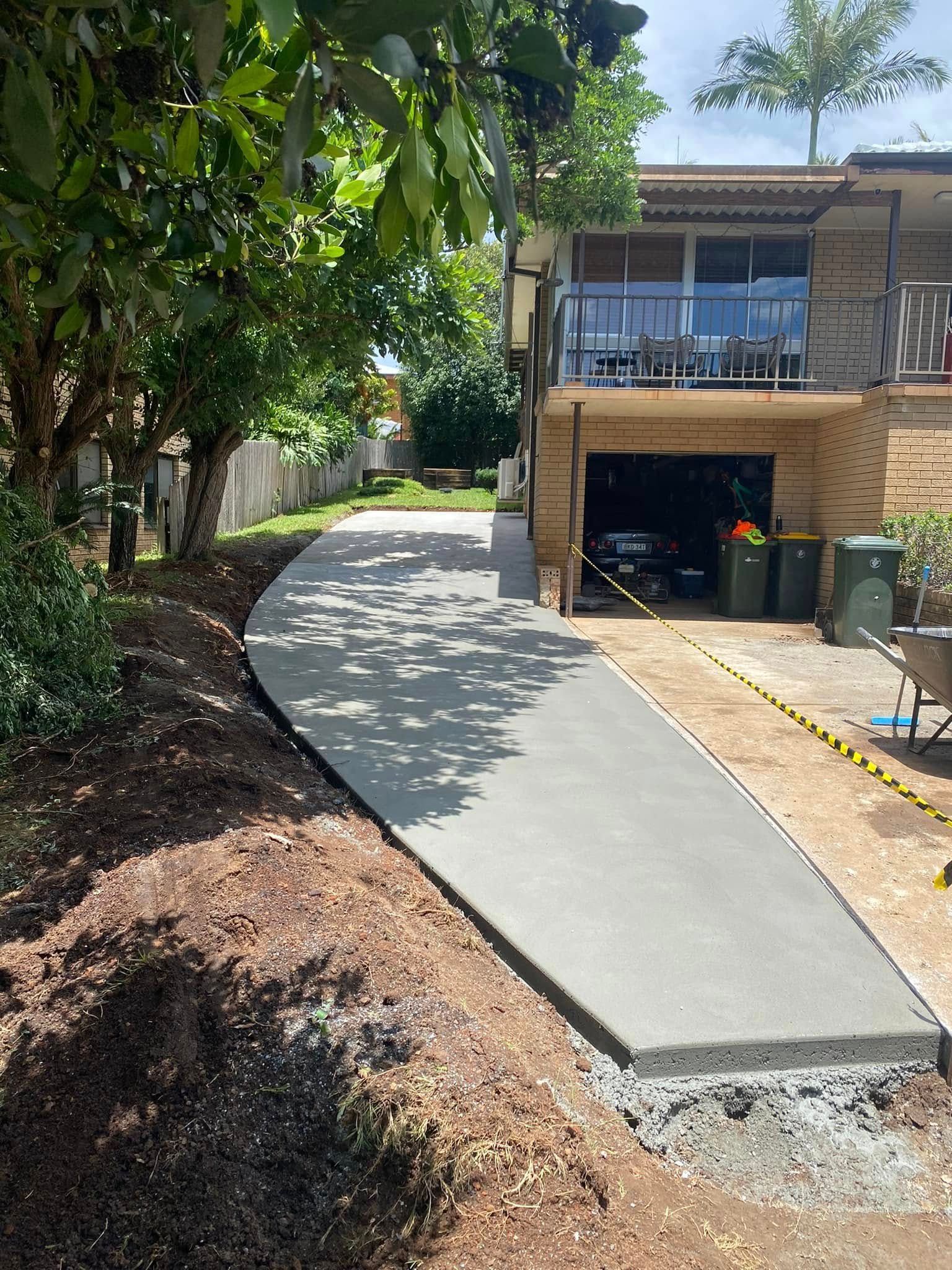 Newly Poured Concrete Driveway Leading to A Garage Under a Two-Story House — Rhyno’s Concreting In Old Bar, NSW