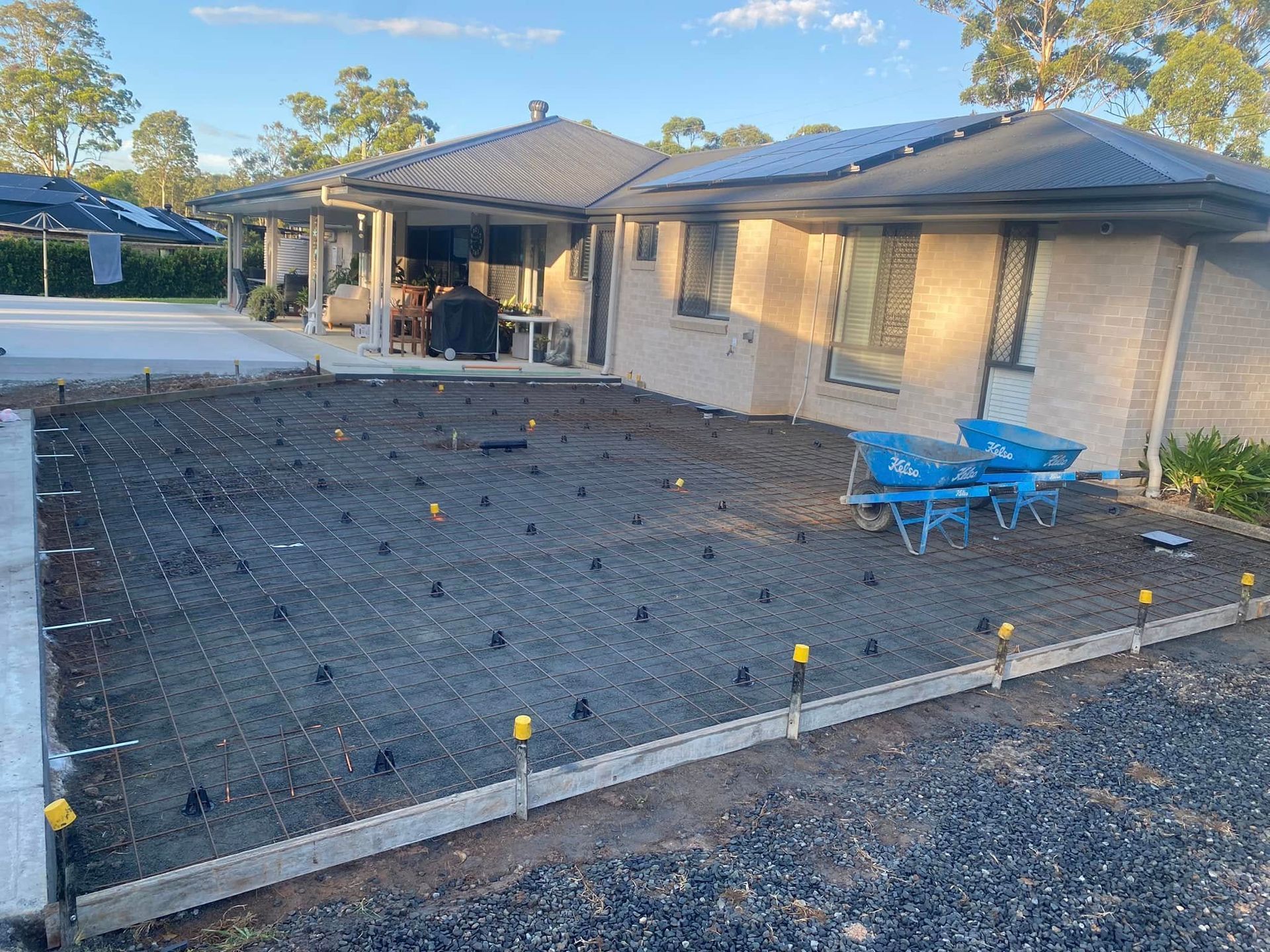 Concrete Slab Under Construction Next to A House with Exposed Rebar and Leveling Markers — Rhyno’s Concreting In Old Bar, NSW