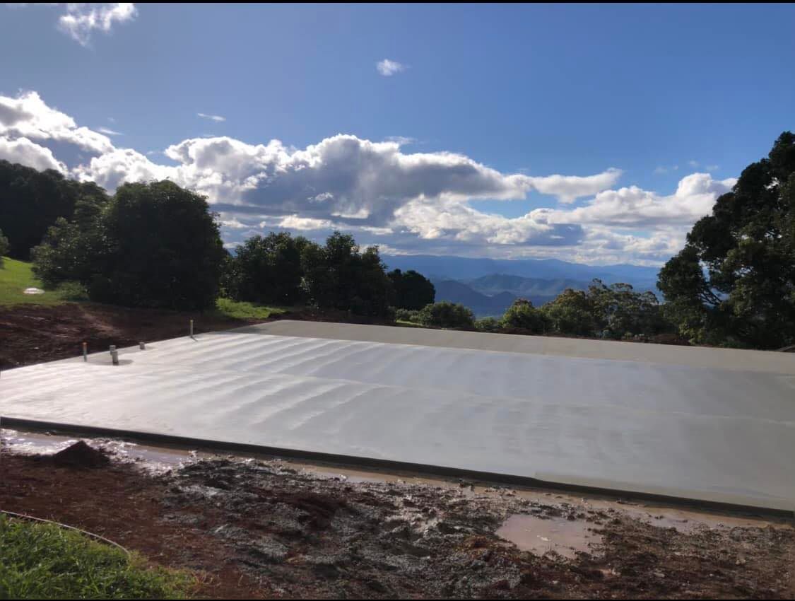 Newly Poured Concrete Slab on A Hillside Overlooking a Valley, Blue Sky with Clouds in The Background — Rhyno’s Concreting In Old Bar, NSW