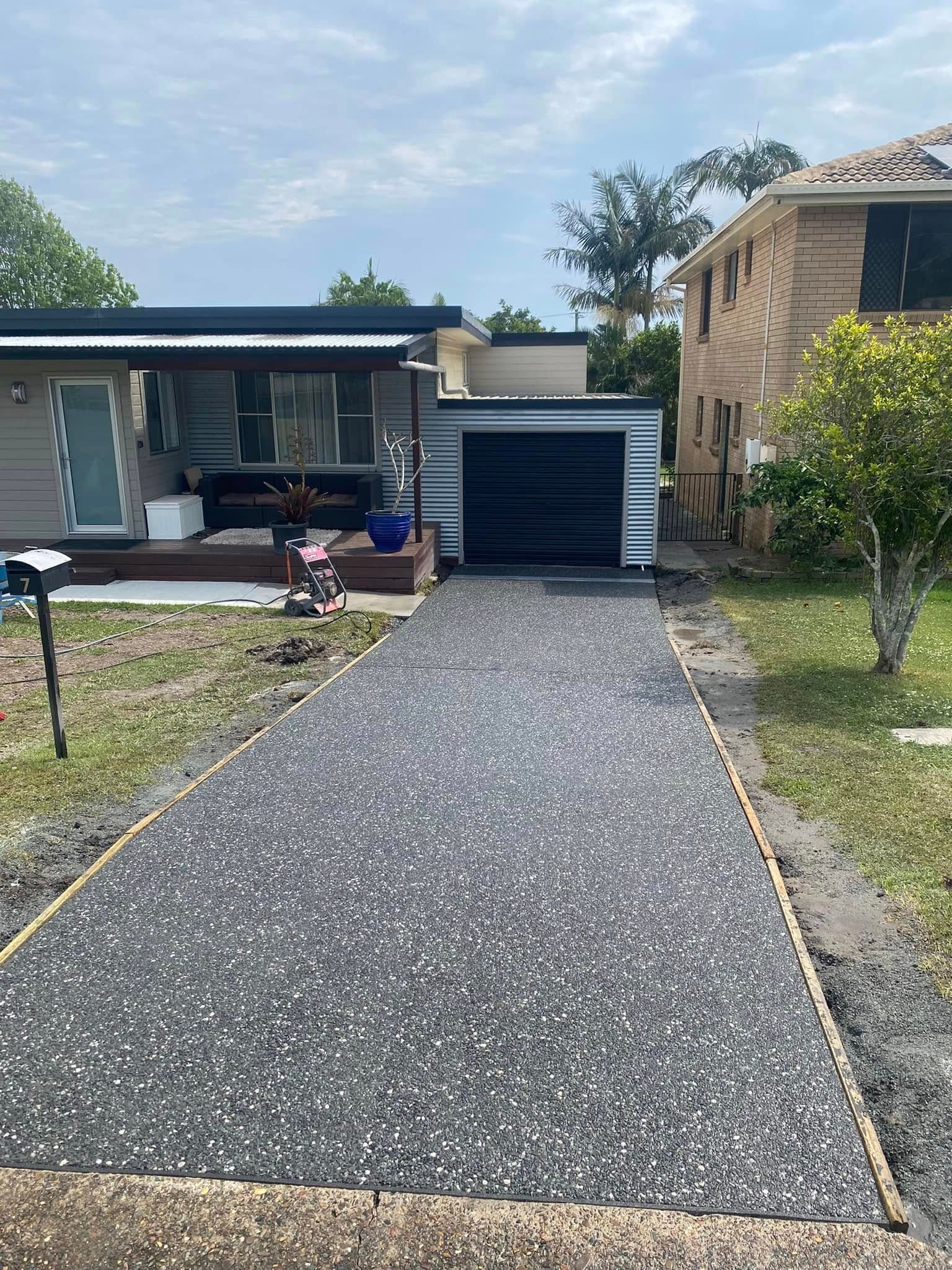 Driveway with Gray Gravel Leading to A Garage and House — Rhyno’s Concreting In Old Bar, NSW