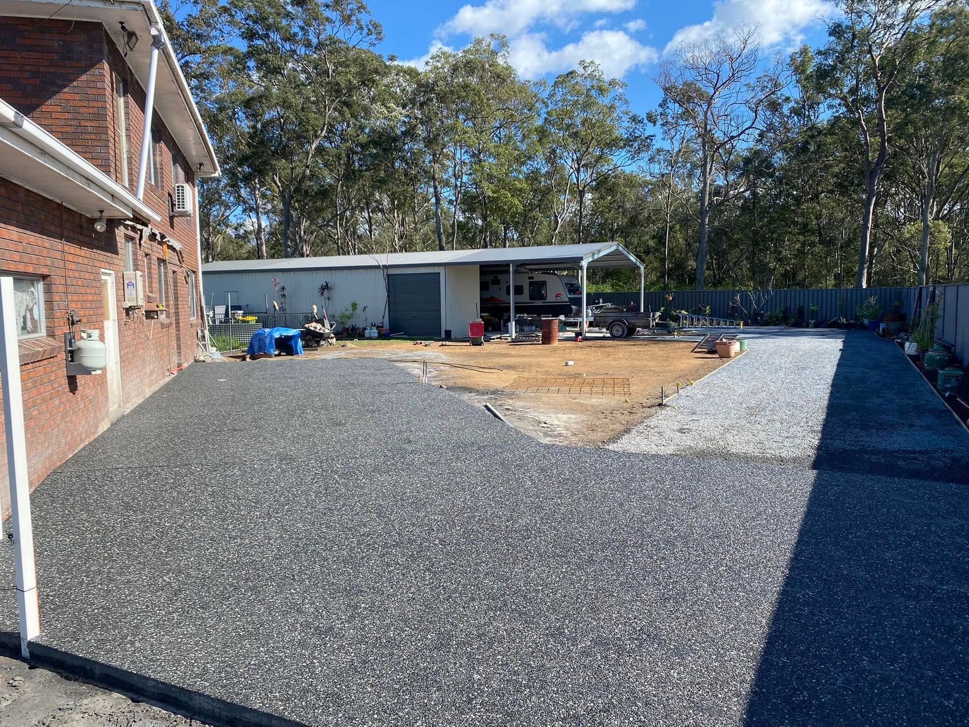 Gravel Driveway Next to A Brick House and A Shed, with A Dirt Area in Between — Rhyno’s Concreting In Old Bar, NSW